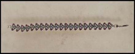A stamped 925 silver panel bracelet of swirl form set with marcasites and rubys. Gross weight 20.4g.