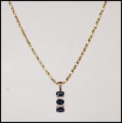 A stamped 375 9ct gold necklace having a pendant set with three oval cut sapphires with white accent