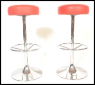 A pair of vintage bar bistro stools raised on central chromed columns terminating in round bases