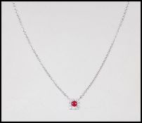 An 18ct white gold necklace pendant set with a a central ruby in a square halo set with diamond