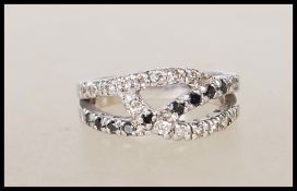 A stamped 925 silver ring of crossover design set with white and black diamonds. Weight 3.4g. Size