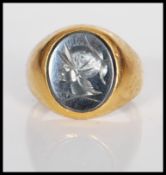 An unmarked 14ct gold signet ring set with an oval black stone to the head engraved with a cameo