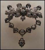 A 19th Century floral diamond and white metal brooch having a central flower flanked by scrolled