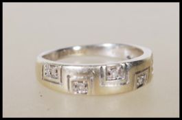 A hallmarked 9ct gold ring set with with five diamonds on a greek key style tapering mount.