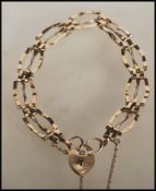 A 9ct gold hallmarked gate link bracelet having a heart padlock and safety chain. Hallmarked London.