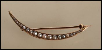 An early 20th Century stamped 15ct gold crescent brooch set with seed pearls, hinge pin with C clasp
