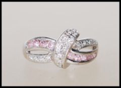 A stamped 375 9ct white gold crossover ring illusion set with white and pink accent stones. Weight