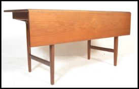 A 20th Century teak wood retro Danish dining table, the table with a single drop leaf raised on