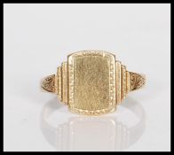 A 9ct gold signet ring having a stepped square head with scrolled decoration shoulders. Marks rubbed