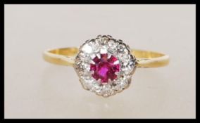 A vintage hallmarked 18ct yellow gold ring set with a central ruby with a halo of diamonds on a