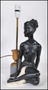 A vintage mid novelty 20th Century table lamp base in the form of a seated semi clad naked black