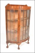 AQn early 20th Century Edwardian walnut Queen Anne revival demi-lune china display cabinet. Raised