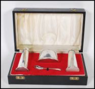 A silver hallmarked cased condiment set consisting of salt and pepperette, mustard pot with blue
