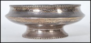 An early 20th Century silver hallmarked footed bowl with a hammered finish set with a George II