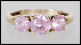 A hallmarked 14ct yellow gold ring set with a central pink stone flanked by two smaller pink stones.