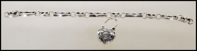 A silver linked bracelet having engraved scroll design to each link with a heart shaped clasp set