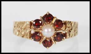 A stamped 9ct yellow gold ring having a decorative flower head mount set with a central pearl and