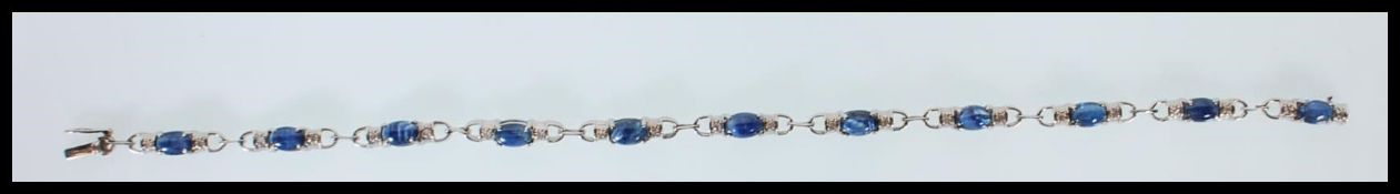 A hallmarked 9ct white gold ladies bracelet set with blue cabochons flanked by white stones. The