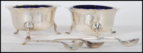 A pair of silver hallmarked table condiments complete with the blue glass liners and hallmarked