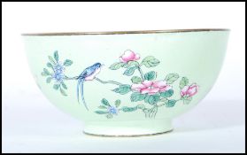 A Chinese enamel pedestal bowl on apple green ground, decorated peonies and butterfly, with a