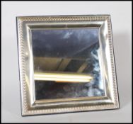 A 20th Century silver framed easel back mirror having repousse decoration borders to the frame,