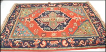 A large 20th Century Persian style floor rug on red ground, central medallion panel framed by