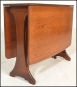 A 1970's teak wood Danish influenced G-Plan drop leaf dining table raised on shaped supports with