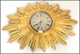 A vintage large 20th Century Art Deco style sunburst starburst rising sun wall clock having a gilt
