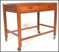 A vintage mid 20th century teak wood butler's tea / drinks trolley having a rectangular top with