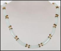 A Chinese jade spacer necklace constructed from 16 curved jade panels mounted on 14ct gold mounts