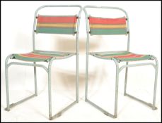 A pair of vintage mid 20th Century metal tubular village hall dispersal chairs, upholstered with a