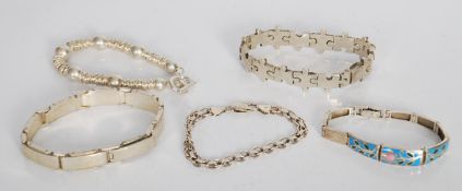 A group of five silver bracelets to include a puzzle bracelet, link and panel examples one having
