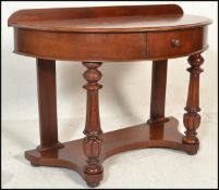 A 19th century Victorian mahogany demi - lune hall table. Raised on turned legs with fitted frieze