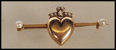 An 20th Century unmarked 9ct gold bar brooch having a central heart motif with a bow to the top, set