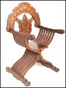 A 20th century hardwood brass inlaid Savonarola throne chair having shaped base with carved back