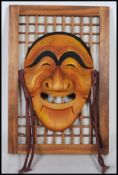 A 20th Century Japanese carved Kabuki / Noh style mask in the form of a stylised elongated face