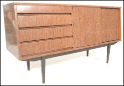 A mid century melamine sideboard credenza being raised on tapering legs with angled wide body