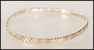 A hallmarked 9ct gold three tone twist design bangle bracelet. Hallmarked London (date marks
