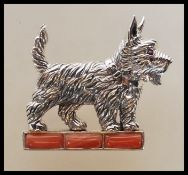 A stamped sterling silver brooch in the form of a West Highland Terrier set with a ruby eye standing