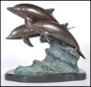 A 20th Century cast brass figurine / ornament in the form of three dolphins riding the crest of a