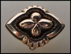 A 19th Century Victorian gold tone mourning brooch of quatrefoil form having a glazed panel to the
