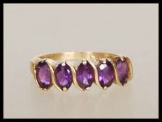 A stamped 10k 9ct gold ring set with five oval cut purple stones. Weight 1.8g. Size M.