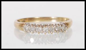 An English hallmarked 9ct gold ring set with a row of seven round cut diamonds. Assay marked