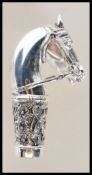 A silver walking stick handle in the form of a horse having floral decorated collar with a central