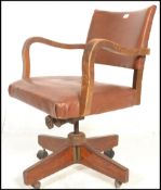 A 1930's Art Deco oak framed swivel desk chair having shaped arm rests being raised on a central