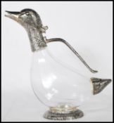 A mid 20th Century silver white metal and glass novelty claret jug in the form of a duck raised on a