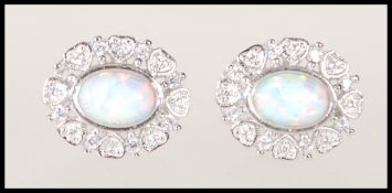 A pair of silver oval flower shaped earrings set with a central opal surrounded by a cluster of Cz'