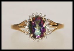An English hallmarked 9ct gold ring set with an oval cut mystic topaz having a halo of white