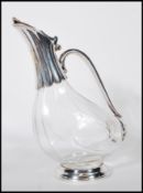 A 20th Century glass claret jug having silver plated mounts stylised in bird form, raised on a