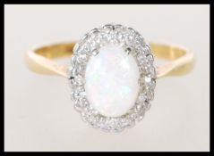 A stamped 18ct gold ladies ring set with an oval opal cabochon having a halo of white stones. Weight